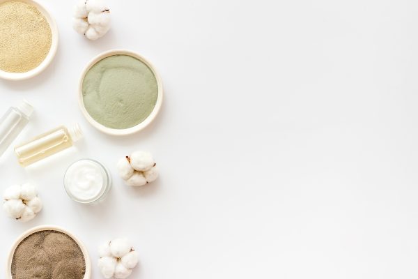 Set of cosmetic clays for facial beauty face mask on white table top-down frame space for text